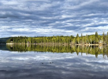 Alaska 'da güneşli bir bahar gününde Birch Gölü' nün sularındaki bulutların ve ağaçların yansıması..