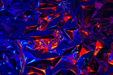 Soyut kırmızı ve mavi alüminyum kırışık folyo arka plan dokusu kırmızı ve mavi ışığı yansıtıyor