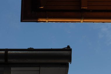 Mavi gökyüzüne karşı alçak açılı çatı yağmuru oluğu