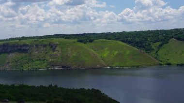 Nehir kıyısındaki yeşil tepelerin panoramik manzarası. Ukrayna, Bakota, panoramik video