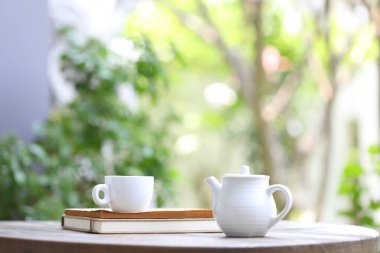 Beyaz çaydanlık ve tahta masa manzaralı beyaz bardak.