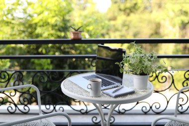 Kahve fincanlı dizüstü bilgisayar ve koridordaki metal masaya demlik.