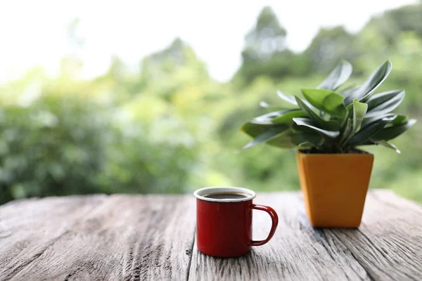 Red coffee mug with plant pot on rustic brown wooden table