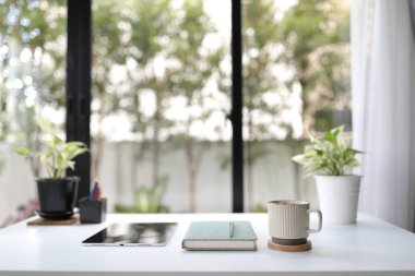 Kahve fincanı, defter ve yeşil santral ofis dekorasyonlu bir çalışma masası.