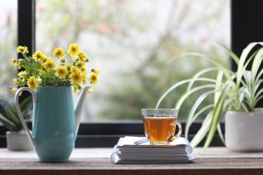Teal tea pot with yellow Chrysanthemum with tea cup and notebook