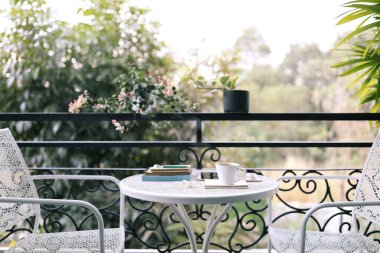 Beyaz kahve fincanı, tablet ve beyaz metal masanın üzerinde defter.