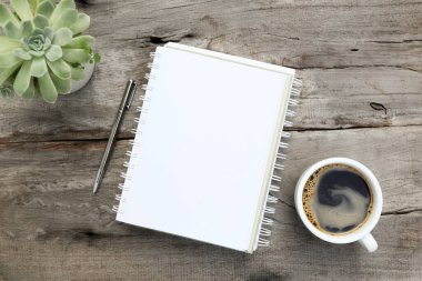 Kahve fincanı ve kaktüs tenceresi düz bir şekilde ahşap masanın üzerinde duruyordu.