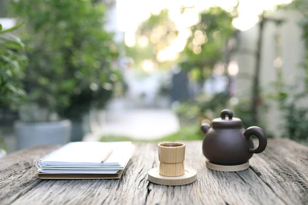 Kahverengi bambu kabı, çaydanlık ve defter açık havada, grunge ahşap masada.