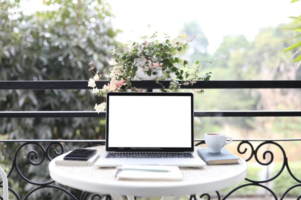 Laptop white mock up blank screen and notebooks on white table outdoor