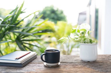 Mavi antika kahve fincanı ve pothos ahşap masaya saksı ve defter dikmek, yazmak için açık havada dinlenme sahnesi