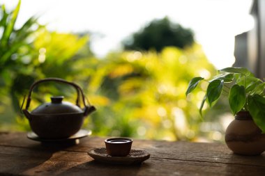 Çay fincanı ve çaydanlık ahşap masanın üzerinde, patates, balkon manzaralı.