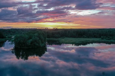 Güzel bir gün batımının havadan görünüşü ve yazın bir gölet, suda gökyüzünün yansıması, çok renkli bulutlar..
