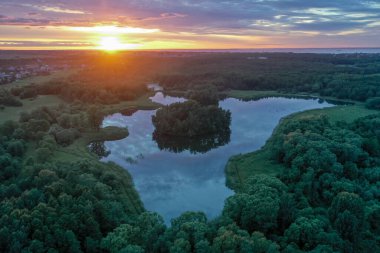 Güzel bir günbatımının panoramik hava manzarası ve yaz sularındaki gökyüzünün yansıması, renkli bulutlar..