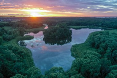 Güzel bir günbatımının panoramik hava manzarası ve yaz sularındaki gökyüzünün yansıması, renkli bulutlar..