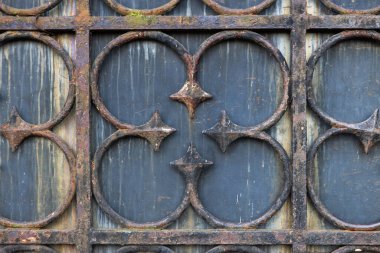 Paslı, metal bir levhanın arka planında eski model sahte çitler var. Antika paslı demir kapının ayrıntıları.