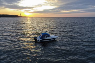 Yaz günü Finlandiya Körfezi 'nde batan güneşe karşı beyaz eğlence teknesi. Sürat teknesi. İyi akşamlar. Güneşin yansıması suda parlıyor.