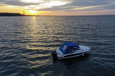 Yaz günü Finlandiya Körfezi 'nde batan güneşe karşı beyaz eğlence teknesi. Sürat teknesi. İyi akşamlar. Güneşin yansıması suda parlıyor.
