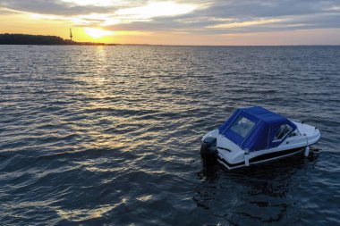 Yaz günü Finlandiya Körfezi 'nde batan güneşe karşı beyaz eğlence teknesi. Sürat teknesi. İyi akşamlar. Güneşin yansıması suda parlıyor.