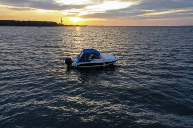 Yaz günü Finlandiya Körfezi 'nde batan güneşe karşı beyaz eğlence teknesi. Sürat teknesi. İyi akşamlar. Güneşin yansıması suda parlıyor.