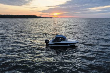Yaz günü Finlandiya Körfezi 'nde batan güneşe karşı beyaz eğlence teknesi. Sürat teknesi. İyi akşamlar. Güneşin yansıması suda parlıyor.