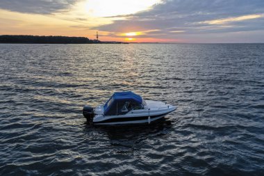 Yaz günü Finlandiya Körfezi 'nde batan güneşe karşı beyaz eğlence teknesi. Sürat teknesi. İyi akşamlar. Güneşin yansıması suda parlıyor.