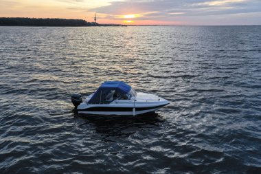 Yaz günü Finlandiya Körfezi 'nde batan güneşe karşı beyaz eğlence teknesi. Sürat teknesi. İyi akşamlar. Güneşin yansıması suda parlıyor.