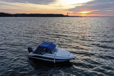 Yaz günü Finlandiya Körfezi 'nde batan güneşe karşı beyaz eğlence teknesi. Sürat teknesi. İyi akşamlar. Güneşin yansıması suda parlıyor.