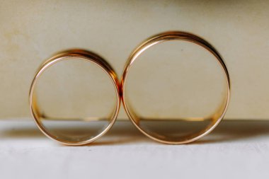 Düğün günü. Altın alyanslar bir kadın parfümünün altın arka planında, düğünle ilgili detaylar. Mutlu bir gün. Yakın plan.