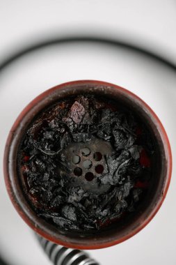 Kırmızı silikon kaplı beyaz tabakta nargile, sigara içtikten sonra yanmış meyve tütünü. Yakın plan.