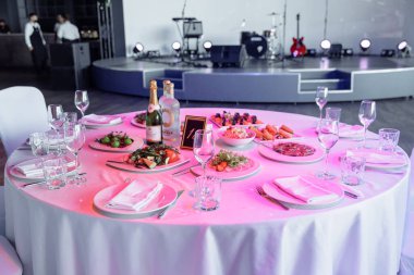 Ziyafet ya da kutlama için masa ayarlayın. İçkiler, şampanya ve meyve suyu için boş şarap kadehleri. Masayı hazırla. Tabakta kumaş peçeteler. Ziyafet salonu. Soğuk mezeler ve salatalar