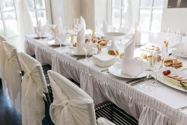 Establecimiento de mesa para un banquete o celebración. Vasos de vino vacíos para licores, champán y jugo. Pon la mesa. Servilletas de tela en bandeja. Sala de banquetes. Aperitivos fríos y ensaladas —  Fotos de Stock