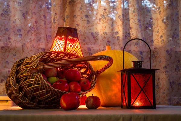 Zucca e cesto di mele ad Halloween nella calda luce delle lanterne, zucca intagliata . — Foto Stock