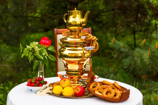 Samovar russo e chá, morangos no prato Gzhel, limões, flores, secagem e bagels — Fotografia de Stock