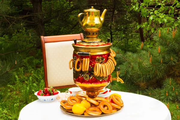 Samovar ruso y té, fresas en el plato Gzhel, limones, flores, secado y rosquillas — Foto de Stock