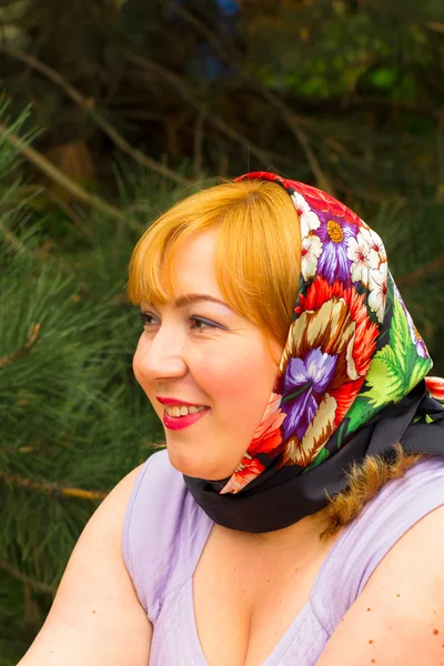 Portrait of a young woman in a flowered silk kerchief on her hea — Stock Photo, Image