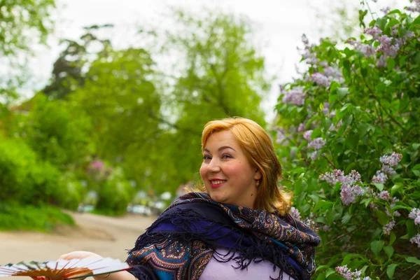 Young woman in motion on the background of blooming lilacs, spar — Stock Photo, Image