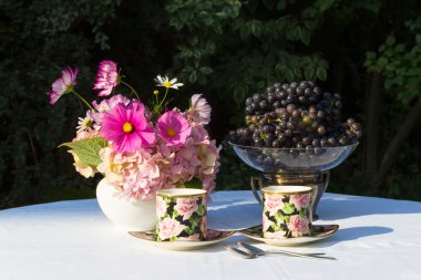 Bouquet of pink flowers, grapes and two cups of English porcelai clipart