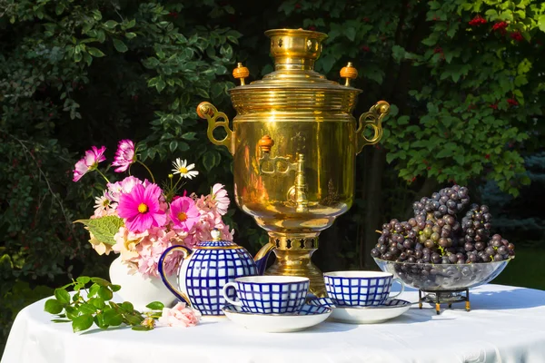 I slutet av sommaren. Samovar, koppar te och höst gåvor - blommor, grönsaker och frukt — Stockfoto