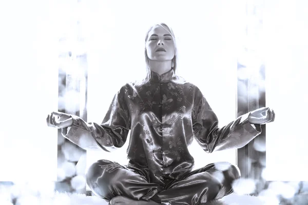 Молода жінка в піжамі сидить в позі лотоса і медитує — стокове фото