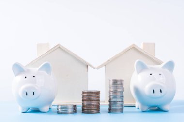 Ahşap evi ve izole edilmiş gri arka planı olan domuz kumbarası. Emlak yatırımı ve konut kredisi finansal konsepti.