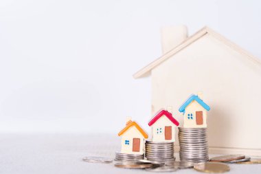 Ev ve yığınla bozuk para izole edilmiş gri arka plan. Emlak yatırımı ve konut kredisi finansal konsepti.
