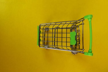 Sarı arka planda alışveriş arabası boş, süpermarket alışveriş konsepti. Bir yazı için yer, üst görünüm. Süpermarkette gıda fiyatları kavramı.