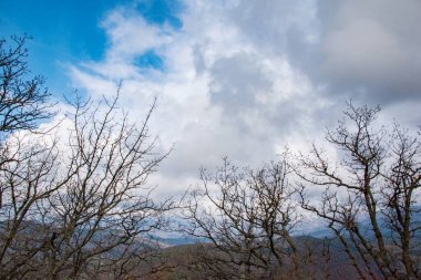 Bereketli beyaz bulutlarla dolu mavi gökyüzü dağların, tepelerin üzerinde asılı. İlkbaharın başlarında, sonbaharın güzel dağlarda manzarası.