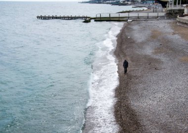 Yalnız bir adam sahil boyunca çakıl taşı plajı boyunca yürür. Üzgün bir adam, yalnız ve düşünceli.,