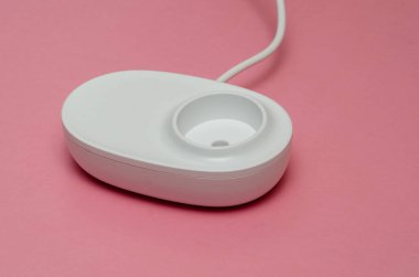 Pembe arka planda elektrikli diş fırçası için kablosuz şarj cihazı