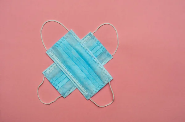 two medical masks in blue on a pink background