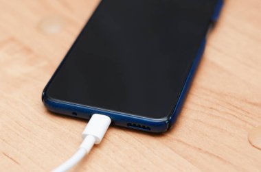Cep telefonu şarj kablosuyla masanın üzerinde duruyor.