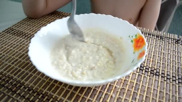 Ragazzo Siede Tavolo Mescolando Porridge Una Tazza Con Cucchiaio Mangia — Video Stock