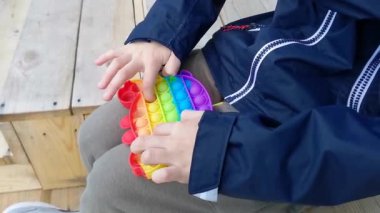 Çok renkli silikon bir oyuncak tak. Çocuk dışarıda oynuyor..