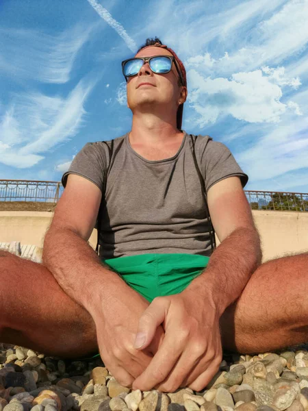 Young Man Green Shorts Shirt Sunglasses Sits Rocky Beach — Stock Photo, Image